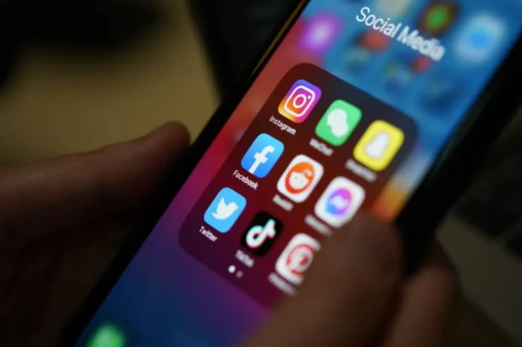 Gros plan sur un écran de smartphone affichant des icônes d'applications de réseaux sociaux comme Instagram, Facebook et TikTok.